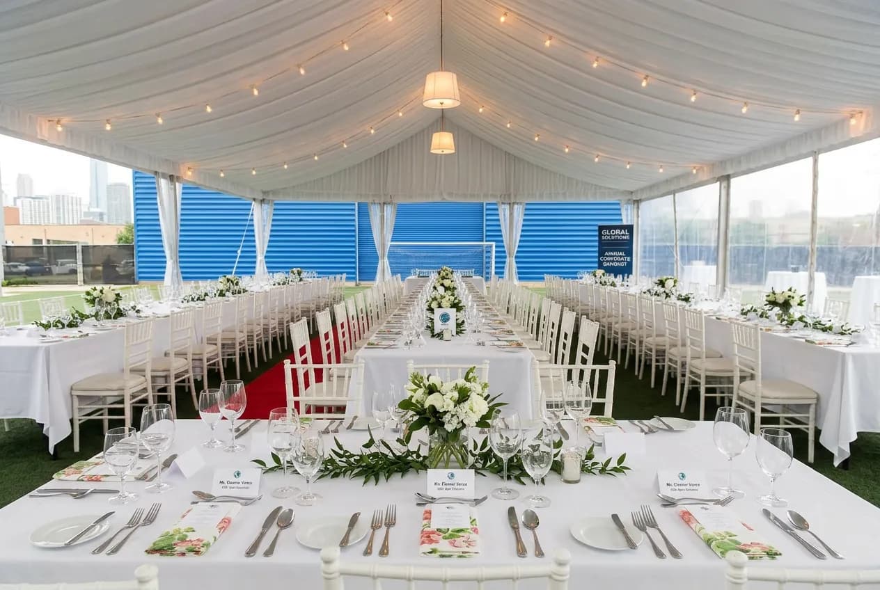 Elegant outdoor event tent setup with banquet tables and string lights
